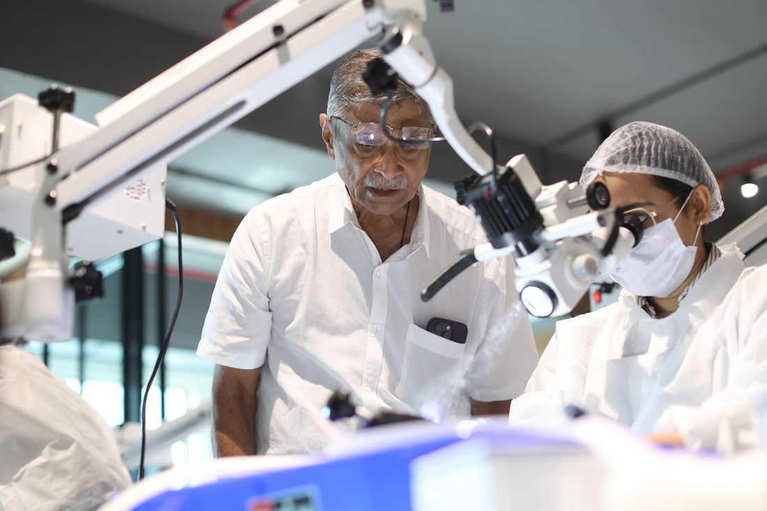 Faculty guiding a delegate at the microscope